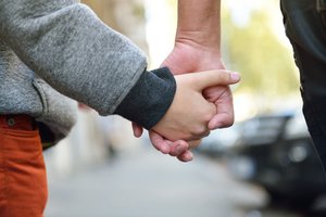 A child holds an adult's hand.