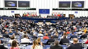 A plenary session of the European Parliament with a speaker at the podium and a crowd of attendees.