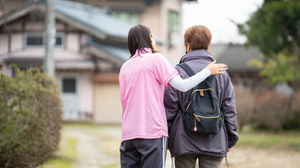 Two people walk together in a rural area.