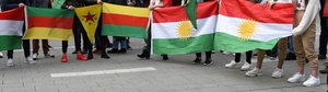Protesters holding Kurdish flags, including Kurdistan and Kurdish YPG flags.