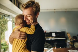 A father holding his baby boy in his arms, looking at him with care