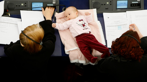 Photograph of a baby, seen from above, lying between two female Members of the European Parliament during a voting session in plenary.
