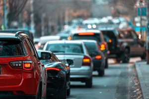 Cars driving along a street in heavy traffic.