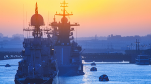 Photograph of military vessels with radar equipment, seen in a port at sunset.