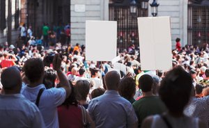 Picture showing a large crowd demonstrating in the street with placards.