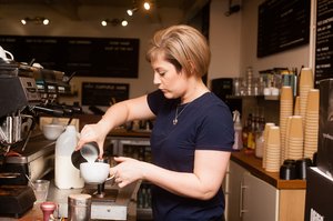 A woman barista preparing a coffee in a coffee shop.