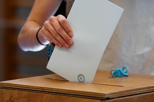 Person  casting their vote in a box at a polling station.