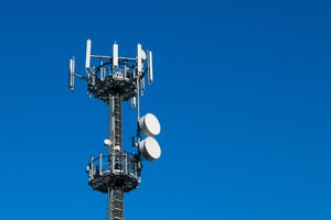 Photograph of a telecommunications tower set against a blue sky.