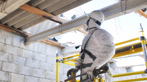 Worker dismantling fiber cement roof with asbestos in an electric station