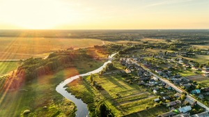 Photograph of a winding river flowing beside a small village seen from the air