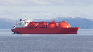 Big red painted LNG (liquefied natural gas) carrier vessel anchored iat a mountainous shoreline