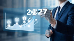 This photograph shows a businessman in a suit pointing to a digital projection of a business growth graph with the year 2027 prominently displayed.