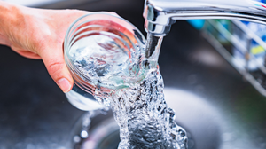 Close-up of a hand filling a glass of water under a kitchen tab