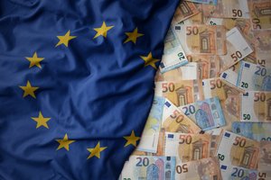 A waving European Union flag next to piles of different euro banknotes