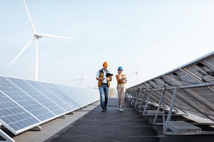Photograph of engineers in hard hats walking through rows of photovoltaic panels