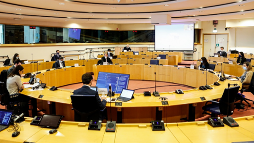 People in a conference room with laptops and microphones.