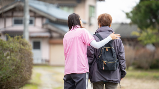 Two people walk together in a rural area.