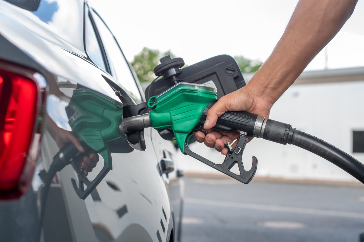 A person refuels a car at a gas station.