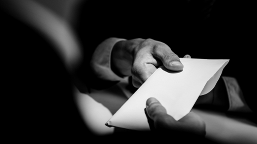Black and white image of men passing a piece of paper between them
