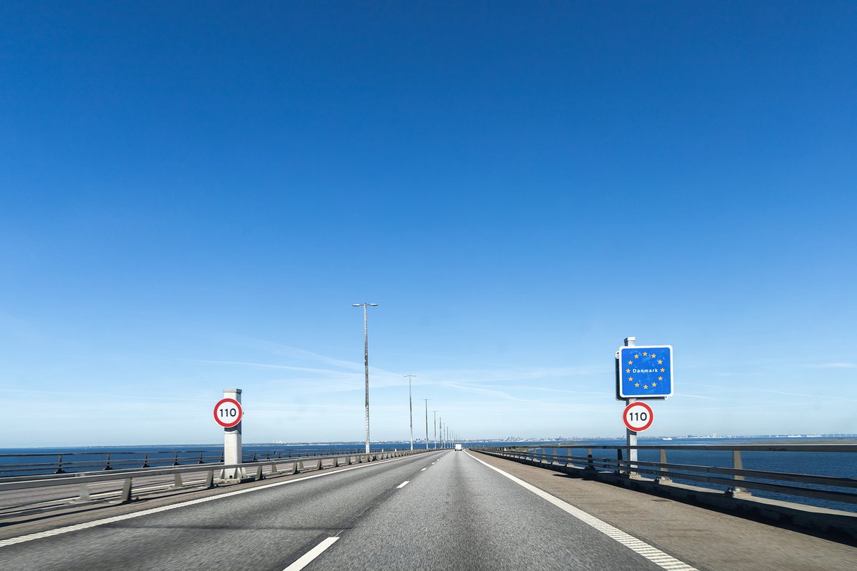 Highway road to Denmark with a sign about crossing the border.