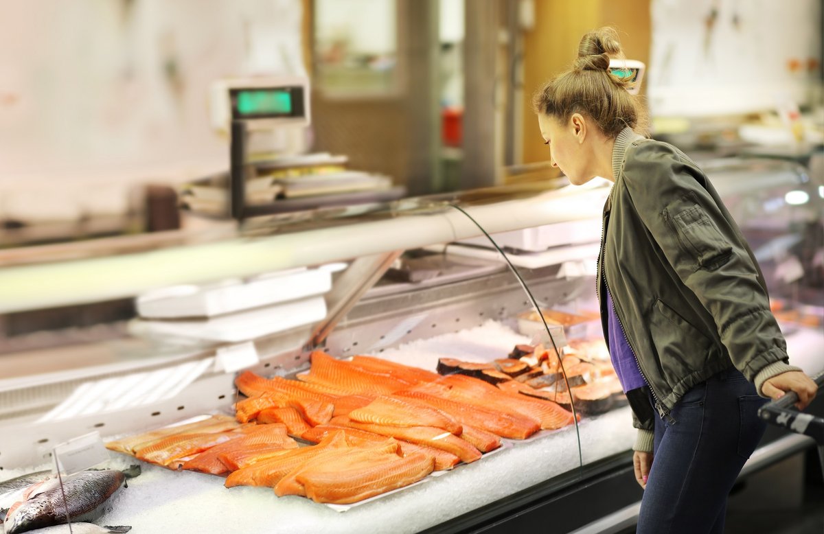 Woman shopping for salmon in a supermarket.
