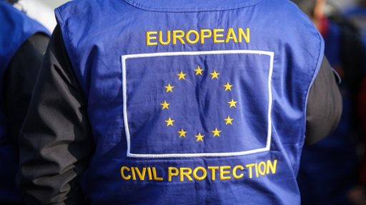 Photograph of a worker in a European Union civil protection vest, seen from behind.