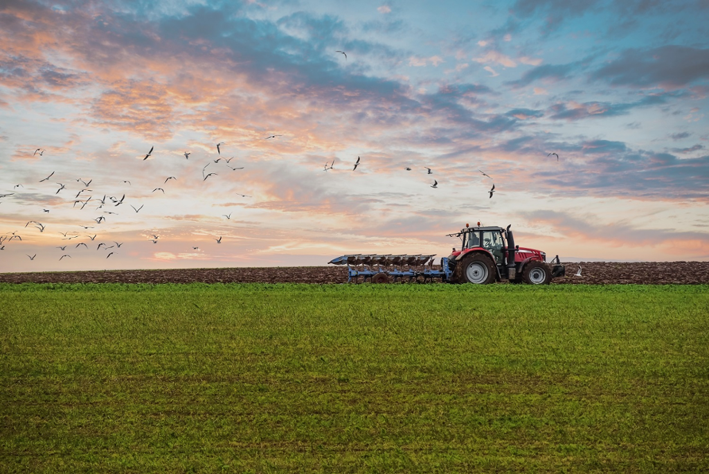 Image of a farmer plowing his fields at sunset