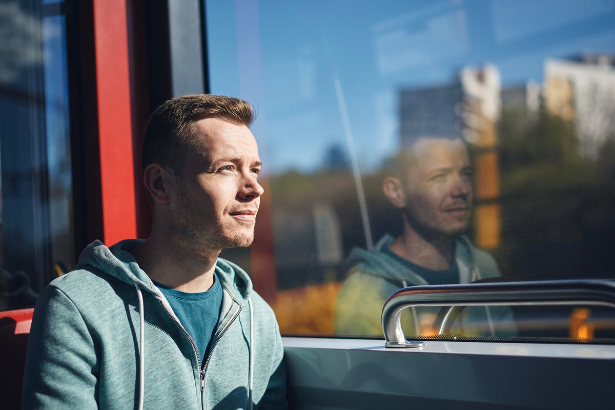 Passenger sitting in front of a window in a public transport vehicle.