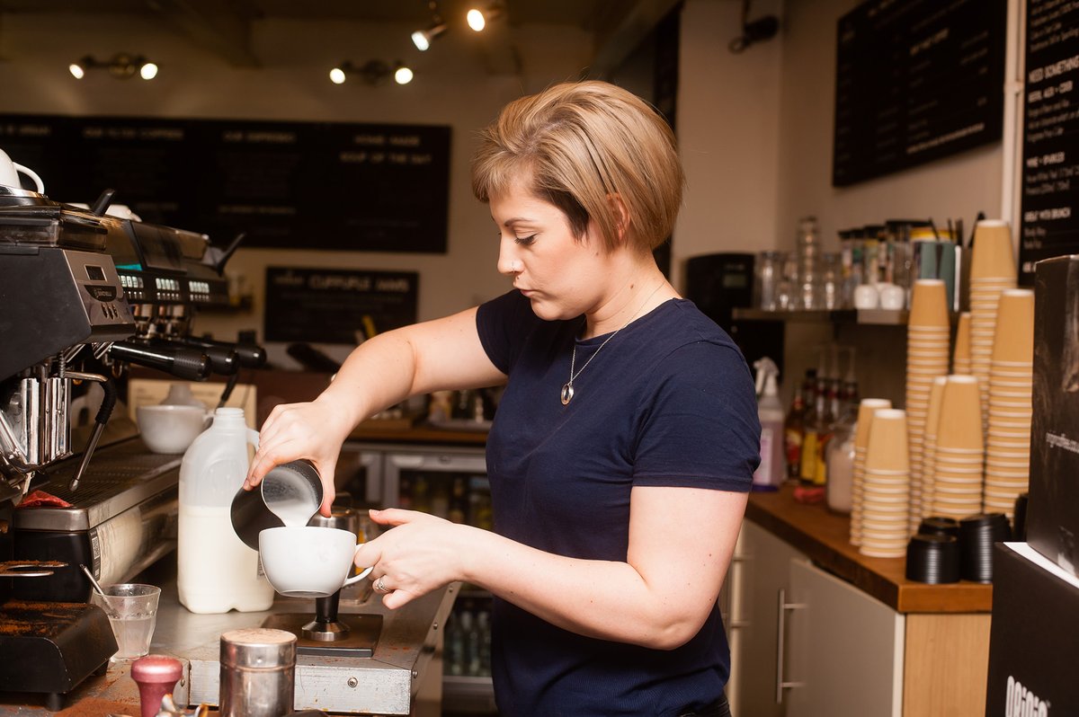 A woman barista preparing a coffee in a coffee shop.