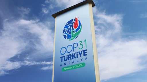 Vertical outdoor banner displaying the logo and details for the COP31 T&uuml;rkiye climate conference against a bright blue sky