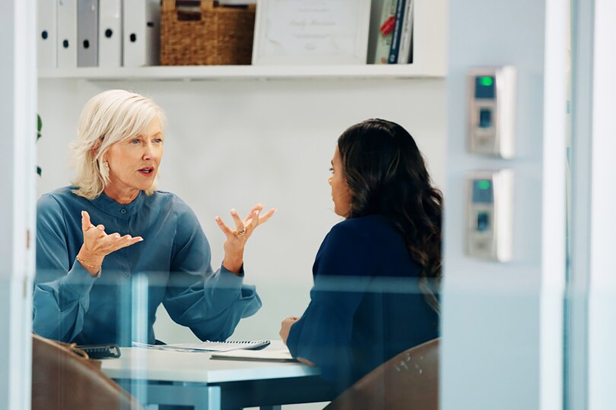 Two women having a conversation in an office environment.