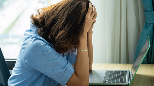 Women sitting in front of her laptop in a position that seems to indicate she's suffering from stress