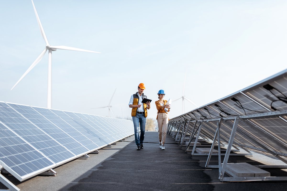 Photograph of engineers in hard hats walking through rows of photovoltaic panels
